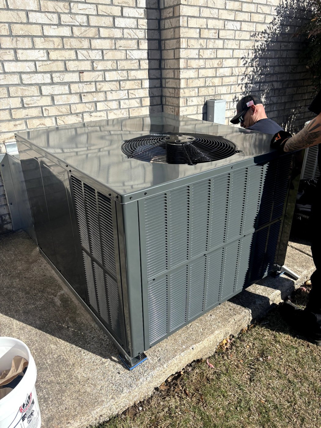 Outdoor AC unit opened for service beside a brick wall